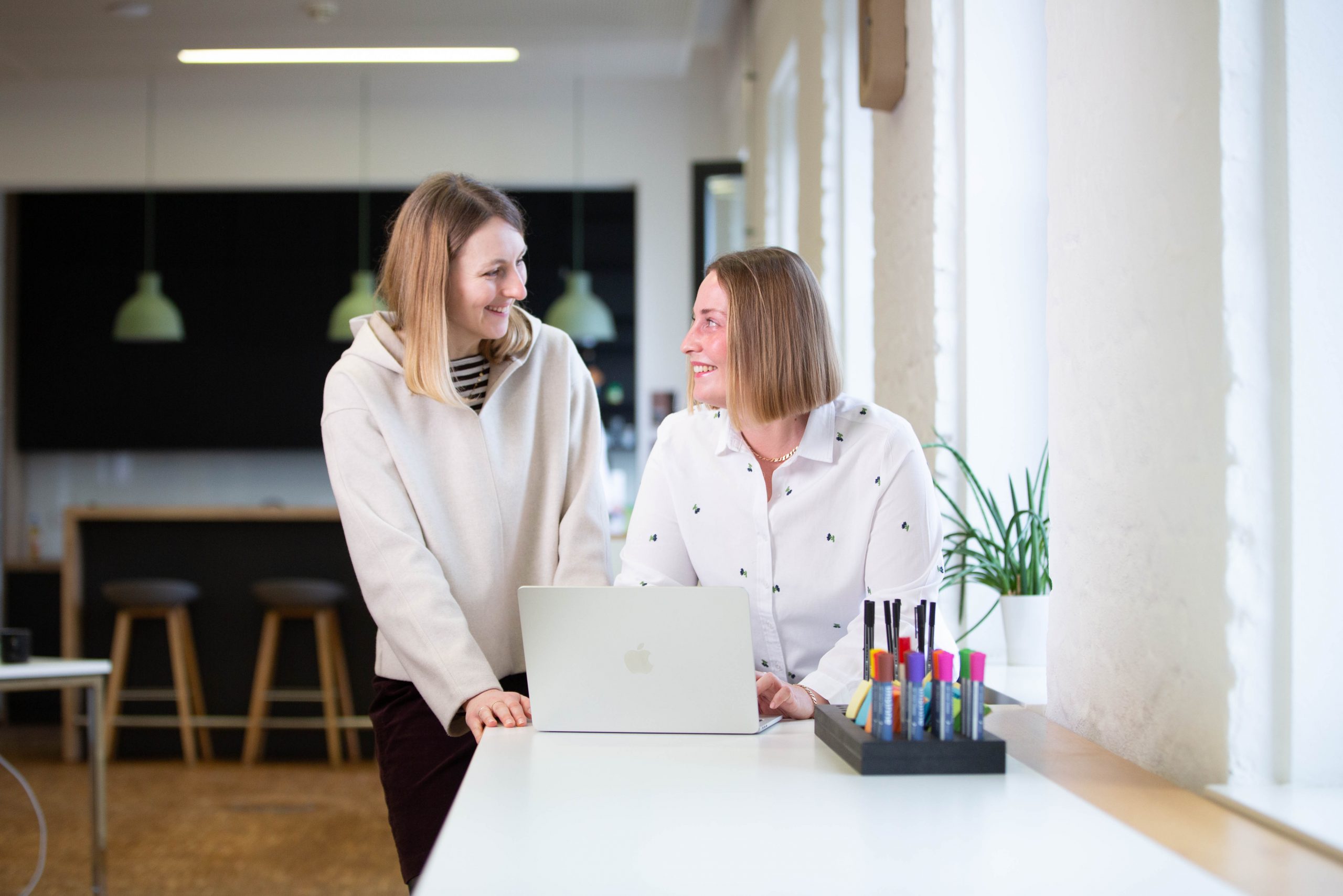 Drei Frauen besprechen sich in einem Meeting – die Stimmung scheint ausgelassen zu sein.