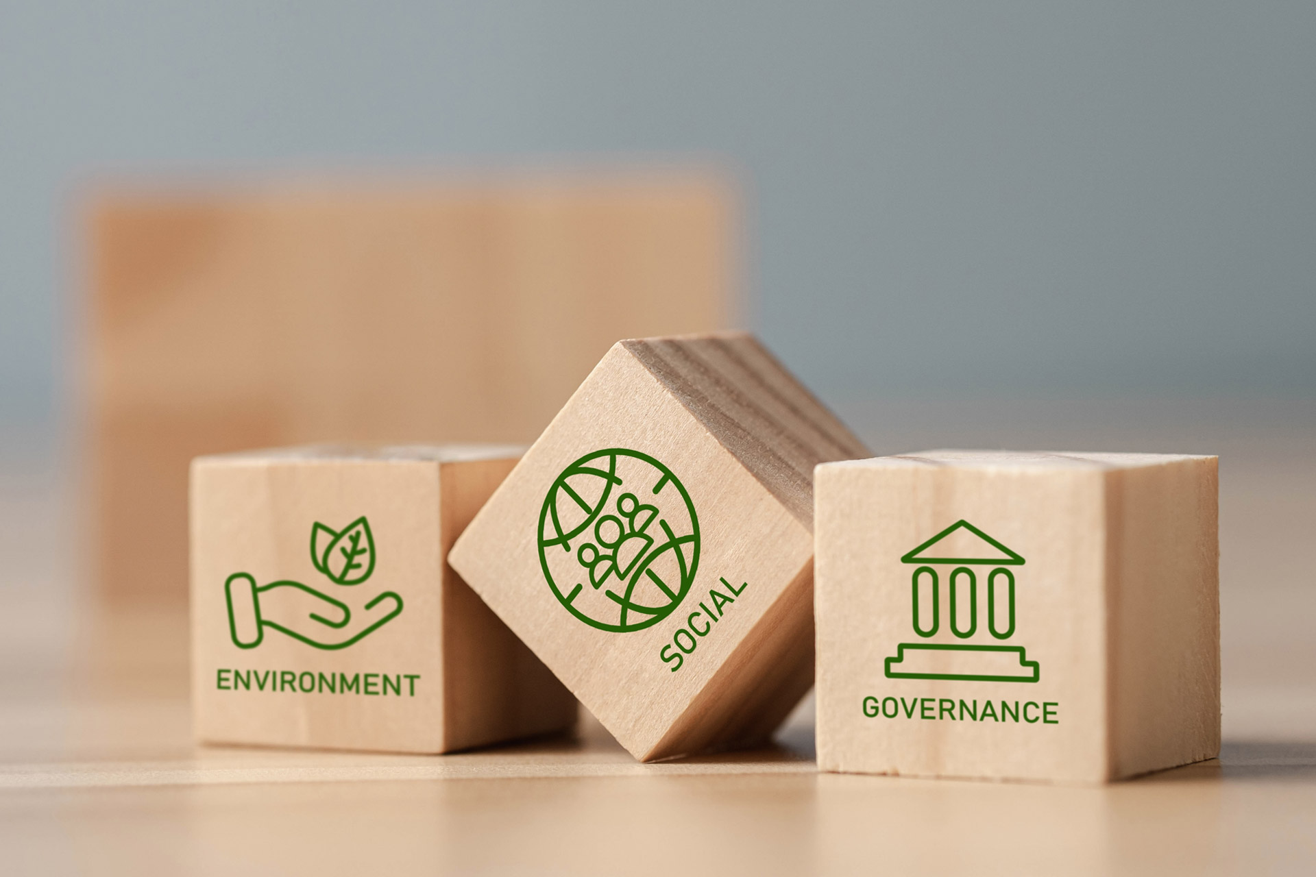 Drei Holzwürfel mit grünen Icons die das ESG-Konzept darstellen.