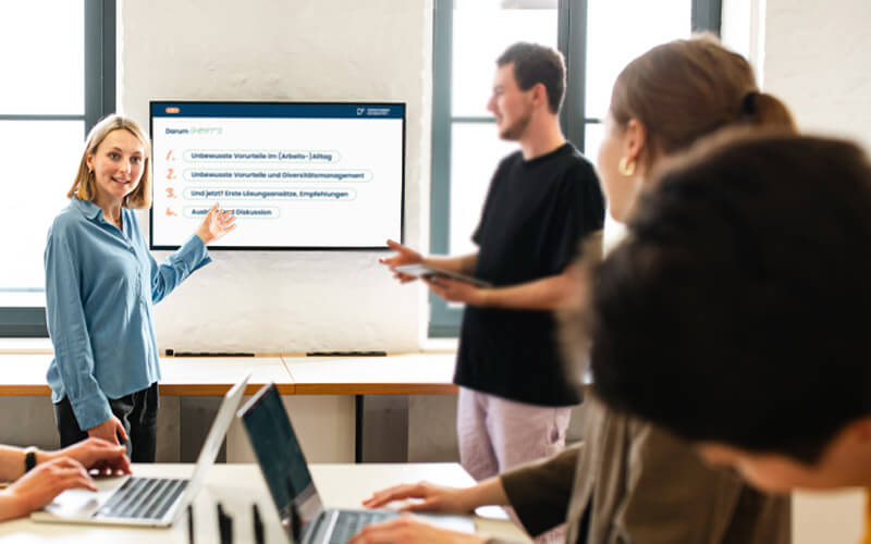 Workshop_Team_gesamt Eine Frau hält einen Präsentation vor ihrem Team.